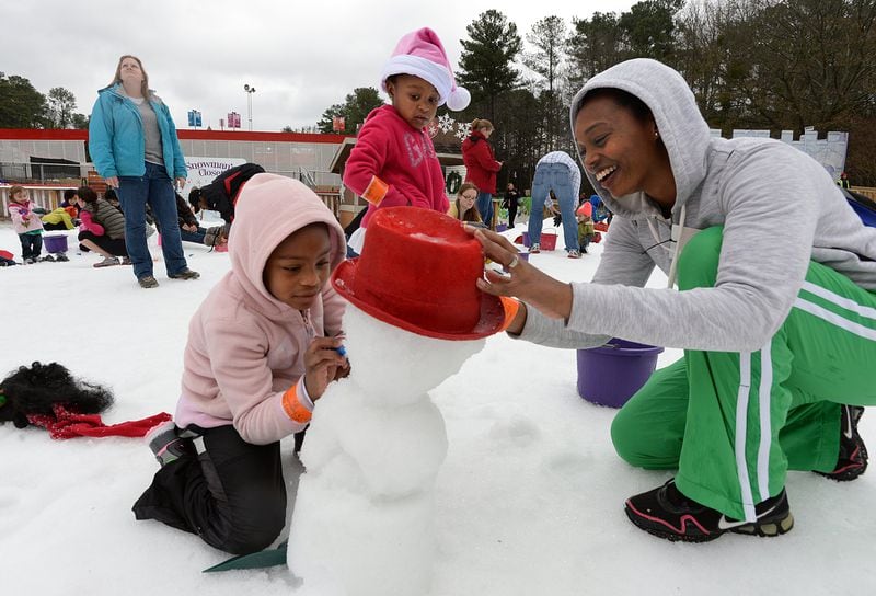 Ladwanya Roberts (right), of Atlanta, and her daughter Aubrey (left), 7, work on a snowman as her daughter Autumn (center), 4, looks in the SnowZone at Stone Mountain Park on Saturday, December 21, 2013. The family came to the Snow Mountain to play with snow and to take advantage of warm temperature. The SnowZone is a winterland with acres of snow play activities.