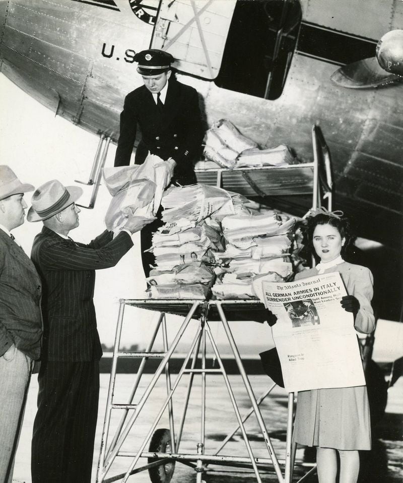 May 3, 1945 - Copies of the Atlanta Journal newspaper are being loaded into a Delta Airlines plane at Augusta, Georgia airport. From left to right: H.R. Walker and Fred Harridge, Journal representatives, watch Jeff Cates, of Delta Air Lines, unload. Mrs. F.C. Jenkins reads the news. Air express editions of The Atlanta Journal were unloaded at the Augusta Airport less than two hours after the papers come off the press the same day in Atlanta.