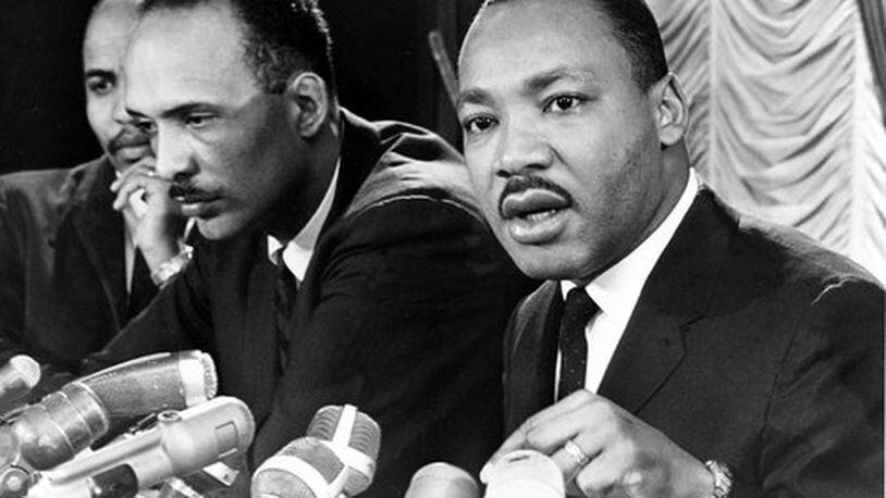 Dr. Martin Luther King Jr., right, speaks at a news conference in Chicago, Ill., Jan. 7, 1966. King, the head of the Southern Leadership Conference, a civil rights organization, announced Chicago as the target of his first major effort in the North in his campaign to clean up slum neighborhoods. Seated at left is Albert Raby, head of the Coordinating Council of Community Organizations, also working for civil rights.