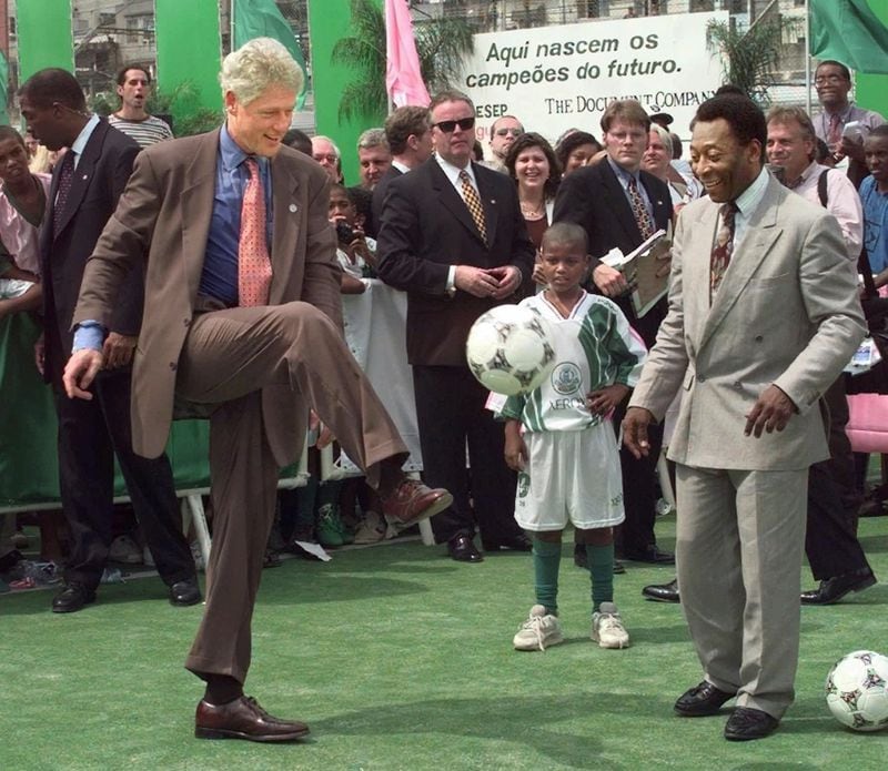 President Bill Clinton takes a turn with the ball as he joins Brazilian soccer legend Pele at the Mangueira School during a visit to Rio de Janeiro on Oct. 15, 1997. Through athletics and academics, the Mangueira project seeks to lift children out of the despair of slum life by teaching them how to build strong bodies and minds. J. SCOTT APPLEWHITE / ASSOCIATED PRESS 1997