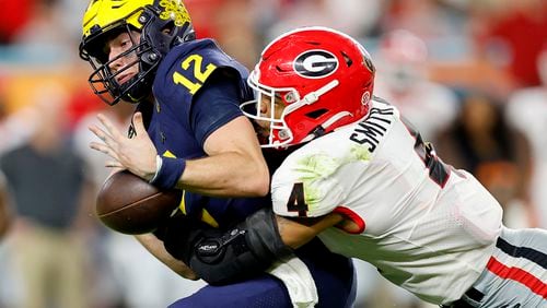 Nolan Smith #4 of the Georgia Bulldogs forces a fumble by Cade McNamara #12 of the Michigan Wolverines in the fourth quarter in the Capital One Orange Bowl for the College Football Playoff semifinal game at Hard Rock Stadium on Dec. 31, 2021, in Miami Gardens, Florida. (Michael Reaves/Getty Images/TNS)