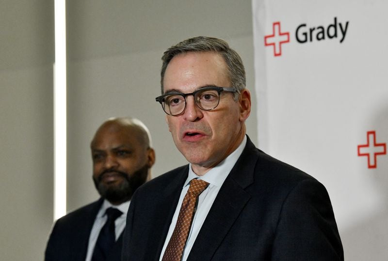 John Haupert, president and CEO of Grady Health System,  speaks to members of the press as Jevon Gibson (background), CEO of The Fulton-DeKalb Hospital Authority, stands behind during a press conference to announce and sign a new deal to subsidize the hospital for indigent medical care at Grady Memorial Hospital, Tuesday, December 9, 2024, in Atlanta. (Hyosub Shin / Hyosub.Shin@ajc.com)