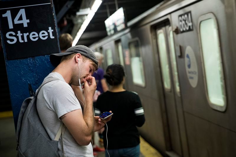 A man looks at his smartphone as a train arrives at the 14th Street subway station, July 20, 2016 in New York City.