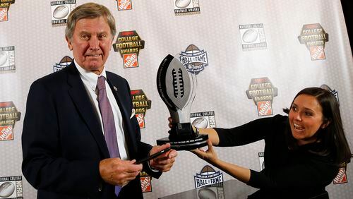 Former coach Steve Spurrier gets help taking a photo of the trophy after being awarded the Contributions to College Football Award on Thursday. (AP photo/John Bazemore)