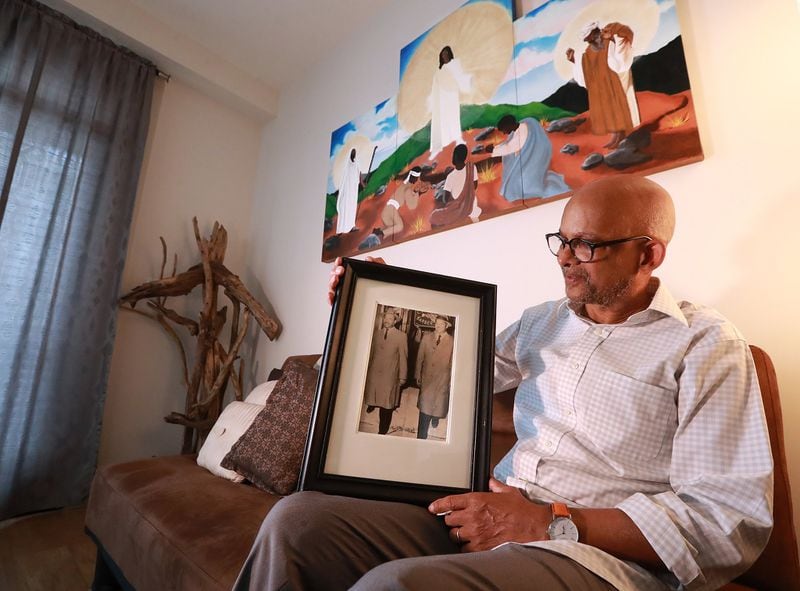 I. Logan Kearse holds a photograph of his dad Reverend Kearse with Martin Luther King Jr. taken in the 1950s during an interview at his residence beneath one of his paintings, this one depicting the Mount of Transfiguration on Tuesday, June 4, 2019, in Decatur. 