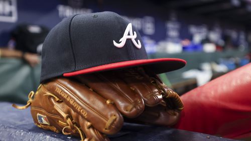 An Atlanta Braves hat and glove are shown near the steps of the dugout in between innings during their game against the Houston Astros at Truist Park, Friday, April 21, 2023, in Atlanta. The Braves lost to the Astros 6-4. Jason Getz / Jason.Getz@ajc.com)