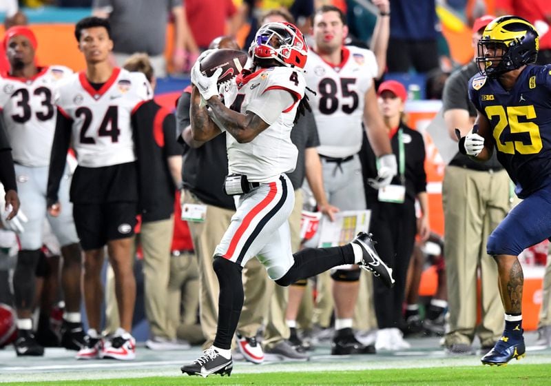 Georgia Bulldogs running back James Cook (4) catches a long pass against Michigan Wolverines linebacker Junior Colson (25) during the second quarter in the 2021 College Football Playoff Semifinal at the Orange Bowl at Hard Rock Stadium, Friday, in Miami Gardens, Fl. (Hyosub Shin / Hyosub.Shin@ajc.com)