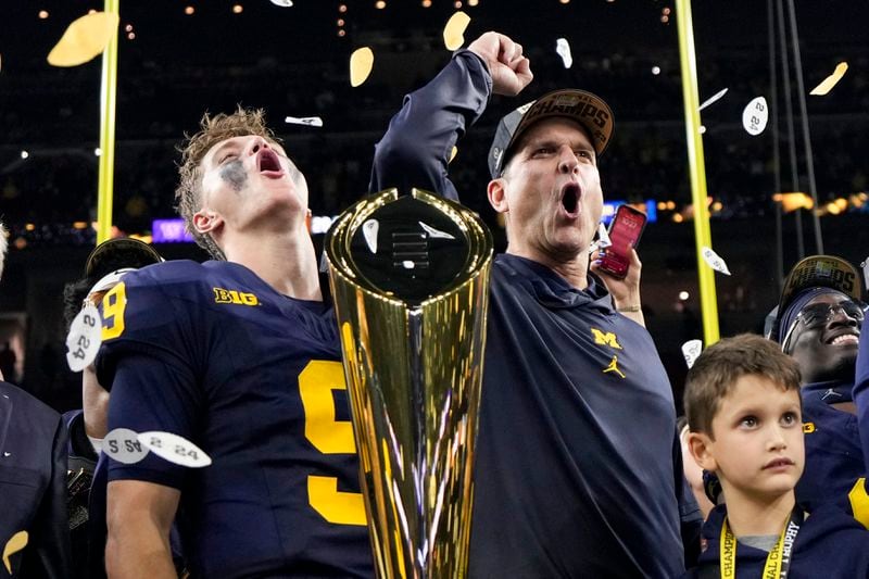 FILE - Michigan head coach Jim Harbaugh and quarterback J.J. McCarthy celebrate with the trophy after their win against Washington in the national championship NCAA College Football Playoff game Monday, Jan. 8, 2024, in Houston. J.J. McCarthy is expected to be the first of many drafted from Michigan’s national championship-winning team. The Wolverines had a record 18 players at the combine. If Jim Harbaugh’s last team has 16 or more players drafted, they will surpass another former champion, Georgia’s 2022 team, that had 15 players selected.(AP Photo/David J. Phillip, File)