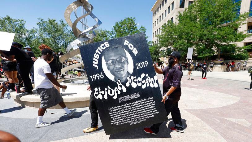 Demonstrators carry a giant placard during a rally and march over the death of 23-year-old Elijah McClain, Saturday, June 27, 2020, outside the police department in Aurora, Colo. McClain died in late August 2019 after he was stopped while walking to his apartment by three Aurora Police Department officers. (AP Photo/David Zalubowski)