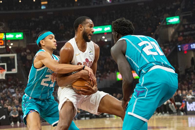 Cleveland Cavaliers' Evan Mobley, center, is tied up by Charlotte Hornets' Tre Mann (23) and JT Thor (21) during the first half of an NBA basketball game in Cleveland, Sunday, April 14, 2024. (AP Photo/Phil Long)