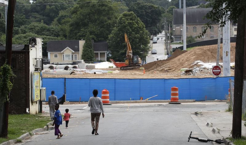 Residents walk to the corner grocery store (left) across the street from the Vine City park that is under construction. Controversy has erupted over naming the park in the historic African American neighborhood after Rodney Mims Cook Sr., a white politician. Bob Andres / bandres@ajc.com