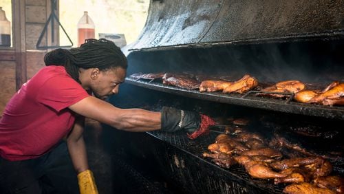 Chef Bryan Furman, shown arranging meat on the smoker at B’s Cracklin Barbecue in Atlanta, plans to rebuild after Wednesday’s fire at his restaurant. CONTRIBUTED BY MIA YAKEL