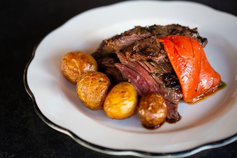 The wood-fired grilled skirt steak with chimichurri, roasted potatoes and roasted piquillo peppers at Fogón and Lions is an homage to chef-owner Julio Delgado's heritage and culinary formation. (RYAN FLEISHER FOR THE ATLANTA JOURNAL-CONSITUTION)