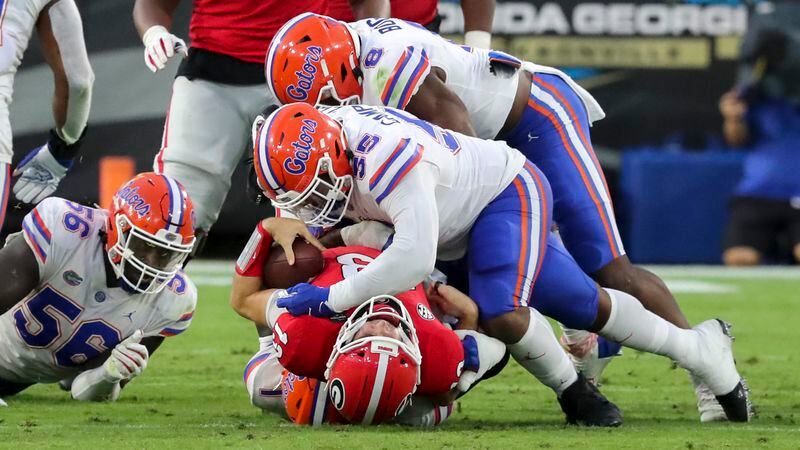 UGA quarterback Stetson Bennett (13) is taken down at the line of scrimmage by Gators defensive lineman Kyree Campbell (55) during Saturday's Georgia-Florida game in Jacksonville, Fla. (Curtis Compton / ccompton@ajc.com)