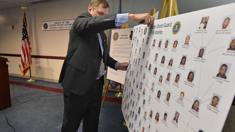 FBI special agent Stephen Emmett uncovers a picture board of 49 indicted current and former correctional officers, inmate and civilians before a press conference on Feb. 11, 2016. More than four dozen current and former state prison guards were arrested Thursday and charged with drug smuggling and accepting bribes. HYOSUB SHIN / HSHIN@AJC.COM