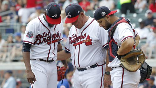 Atlanta Braves starting pitcher Julio Teheran, left, talks with pitching coach Chuck Hernandez, center, as catcher David Freitas looks on in the first inning of a baseball game against the New York Mets in Atlanta, Sunday, Sept. 17, 2017. (AP Photo/Tami Chappell)