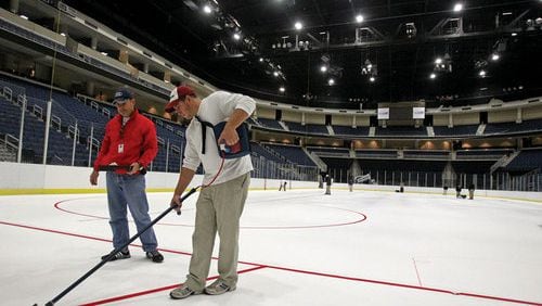 Ryan Guley (right) and ice technician Bob Caswell paint red lines on the ice in 2011 at Gwinnett Arena, now known as Infinite Energy Arena. (Jason Getz/AJC file)