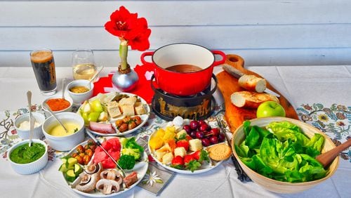 Winter is the perfect time for fondue. In the pot is Chocolate Fondue; the tray below it has accompanying items, such as strawberries, pineapple, pound cake, marshmallows and cherries. The upper tray (left) has items for Cheese Fondue, including sliced apples, crusty bread, gherkins and pickled onions. On the left are sauces for Beef Fondue; the lower tray (left) has items for that fondue, including mushrooms, broccoli, zucchini and roasted potatoes. (Styling by Lisa Hanson / Chris Hunt for the AJC)