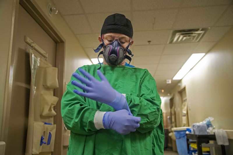 A nurse at Tanner Health System in Carrollton prepares to enter a patient's room on the COVID-19 isolation floor earlier this month.  Perhaps the severest factor in the overflow of hospitals is a nationwide shortage of nurses trained to deal with very ill patients.  (PHOTO by Alyssa Pointer / Alyssa.Pointer@ajc.com)