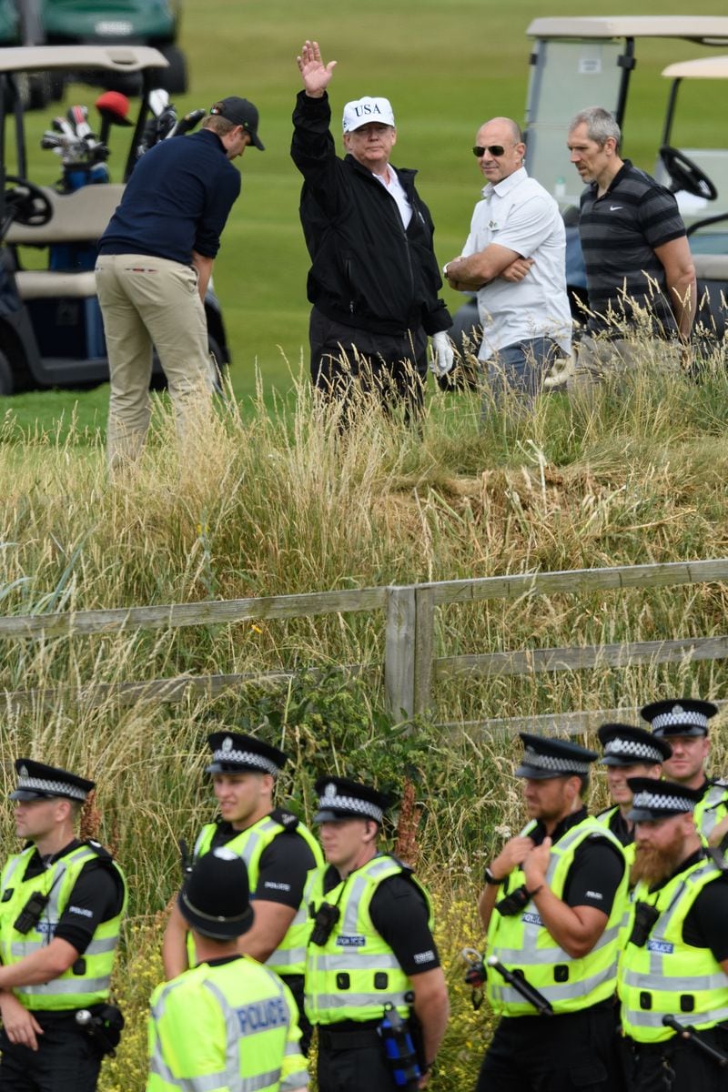 U.S. President Donald Trump (C) waves as he plays golf at Trump Turnberry Luxury Collection Resort during the President's first official visit to the United Kingdom on July 14, 2018 in Turnberry, Scotland.
