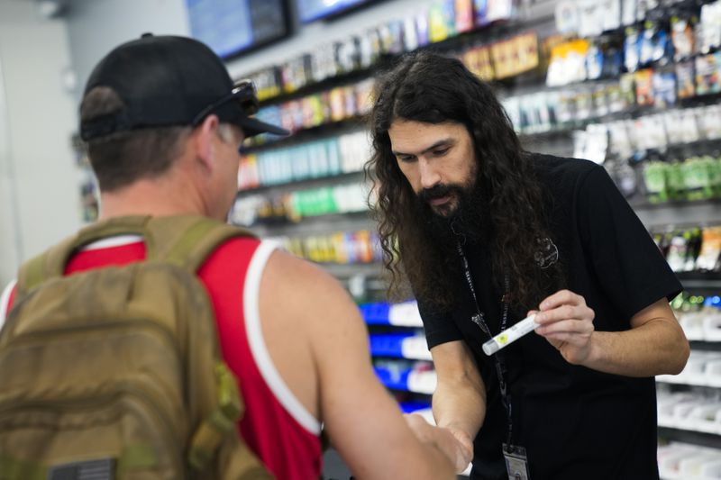Cloud 9 Cannabis employee Beau McQueen, right, helps a customer, Saturday, April 13, 2024, in Arlington, Wash. The shop is one of the first dispensaries to open under the Washington Liquor and Cannabis Board's social equity program, established in efforts to remedy some of the disproportionate effects marijuana prohibition had on communities of color. (AP Photo/Lindsey Wasson)
