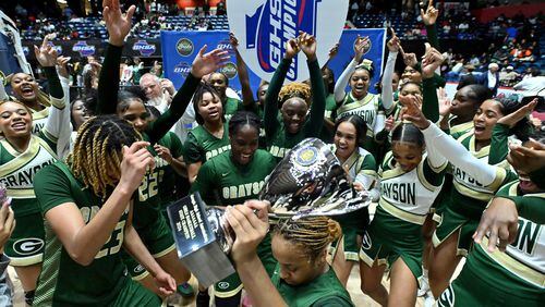 Grayson's Malaya Jones (front) holds the championship trophy and celebrates with teammates and cheerleaders after the team's 65-44 victory over North Paulding Saturday in the Class 7A girls title game.  (Hyosub Shin / Hyosub.Shin@ajc.com)