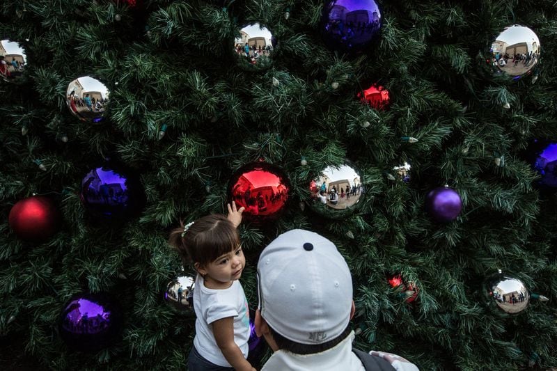 With her father, Chris Patten, watching, Catalina, 19 months old, reaches for a Christmas ornament hanging from the Great Tree at the Domain in 2014. Tamir Kalifa for American-Statesman 2014