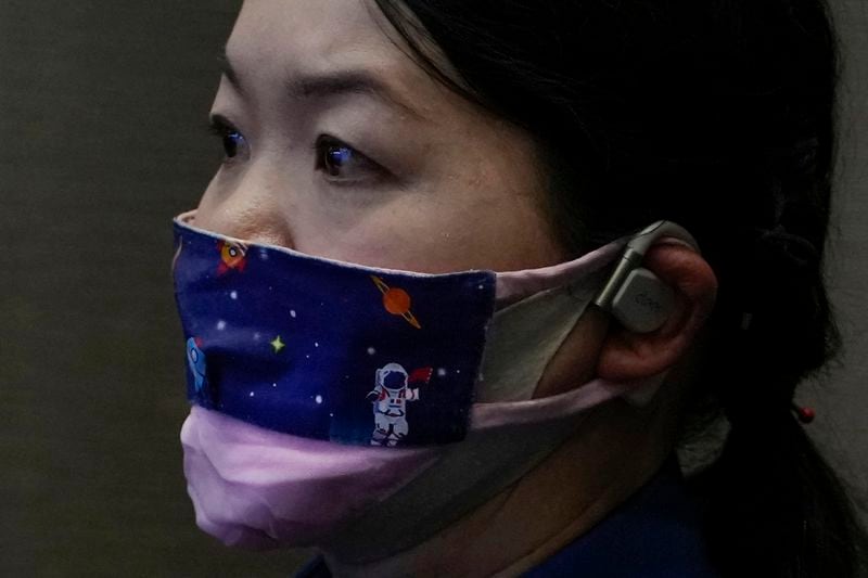 A staff member wearing a face mask depicting a Chinese astronaut in a space attends a news conference for an upcoming Shenzhou-18 mission at the Jiuquan Satellite Launch Center in northwest China, Wednesday, April 24, 2024. (AP Photo/Andy Wong)
