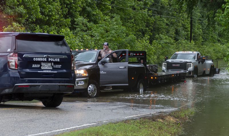 Drivers disregard a Conroe Police Department road block and travel down a flooded road, Thursday, May 2, 2024, near Sapp Road in Conroe, Texas. (Kirk Sides/Houston Chronicle via AP)