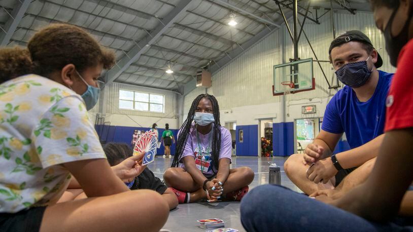 Camp counselor Jada Faulks, center, watches as camp counselor Ethan Sandhagen, right, plays a card game with campers at the Hugh Grogan Community Center in Marietta, Thursday, June 10, 2021. The camp is sponsored by the Marietta Police Athletic League. (Alyssa Pointer / Alyssa.Pointer@ajc.com)
