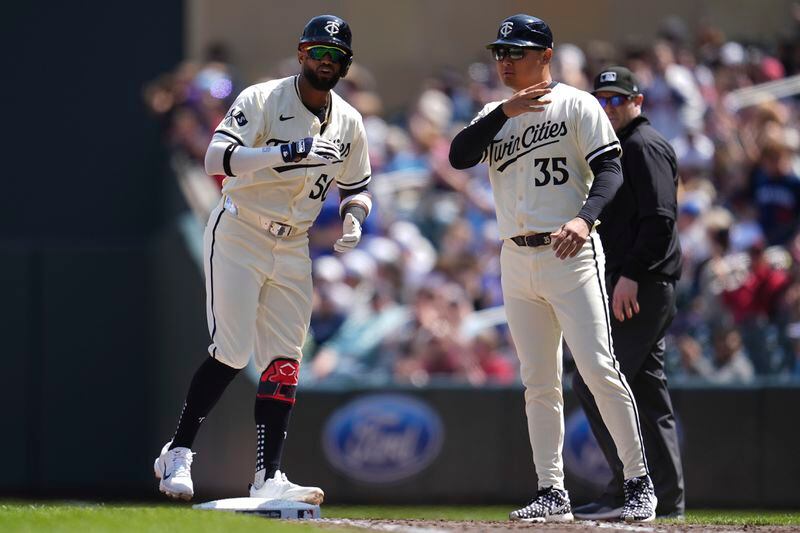 Minnesota Twins' Willi Castro, left, celebrates after hitting an RBI-single during the sixth inning of a baseball game against the Chicago White Sox, Thursday, April 25, 2024, in Minneapolis. At right is Twins coach Hank Conger. (AP Photo/Abbie Parr)