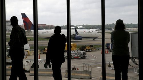 Delta Air Lines passengers watch as a Delta plane taxis at Hartsfield-Jackson. (AP Photo/Charles Rex Arbogast, File)