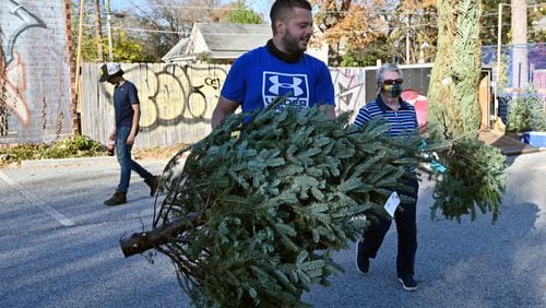 Kevin Goez, manager, helps Pat Redmond, long-time customer, with loading her Christmas tree at Northstar Christmas Trees in East Atlanta on Thursday, December 2, 2021. (Hyosub Shin / Hyosub.Shin@ajc.com)