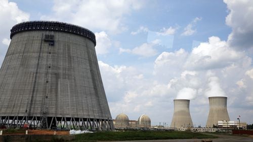 In this 2014 photo, a new cooling tower for a nuclear power plant reactor that's under construction stands near the two operating reactors at Plant Vogtle power plant in Waynesboro, Ga. AP/John Bazemore