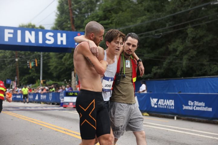 Runner Andrew Jones is assisted at the finish of the 54th running of the Atlanta Journal-Constitution Peachtree Road Race in Atlanta on Tuesday, July 4, 2023.   (Jason Getz / Jason.Getz@ajc.com)