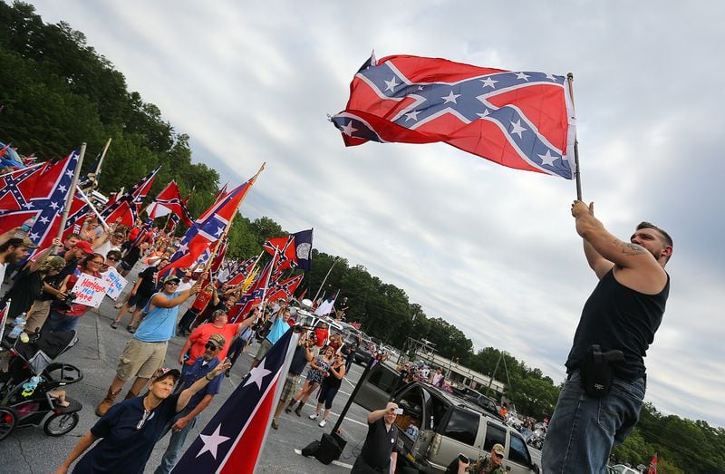 080215 STONE MOUNTAIN: Travis Conklin, Barnesville, waves a flag from the top of his truck durig a pro-Confederate flag rally at Stone Mountain Park on Saturday, August 1, 2015, in Stone Mountain. Curtis Compton / ccompton@ajc.com