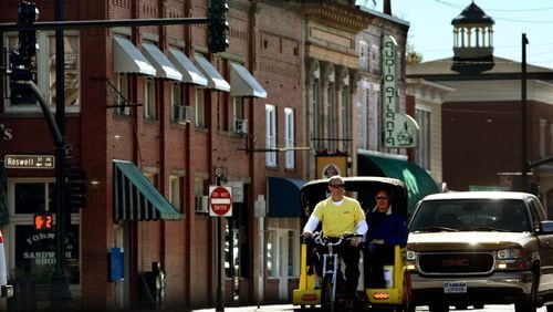 Brian Buckalew, owner of Marietta Pedicabs, gives a ride to customers in historic Marietta Square on a November morning in 2010. Woodstock is moving to adopt a pedicab ordinance adapted from Marietta’s. AJC FILE / Jason Getz / jgetz@ajc.com