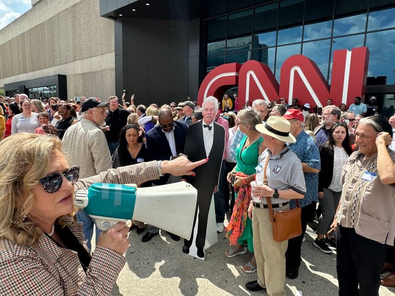 CNN alum Marylynn Ryan, organizer of the CNN Center farewell photo and reception, uses a bullhorn to corral the troops before the photo shoot on June 1, 2023, the 43rd anniversary of CNN's launch. Ted Turner wasn't there but a cardboard cutout of him was. RODNEY HO/rho@ajc.com