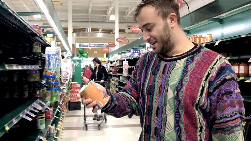 Griffin Brody grabs some canned food as he makes a grocery run for a person who requested it online in Charlotte, N.C. on March 14, 2020. Brody offered online to help the elderly or those who may be at risk during the coronavirus pandemic. Joshua Komer/Charlotte Observer/TNS