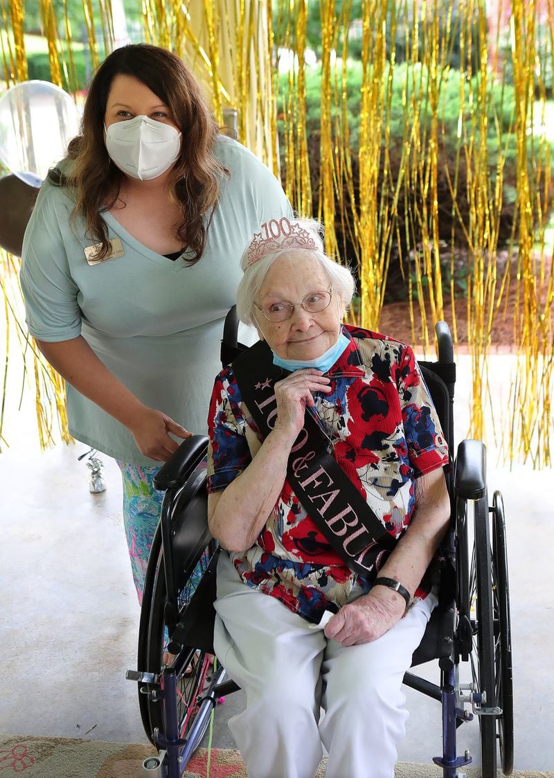 Westbury Medical Care & Rehab administrator Jennifer Vasil helps COVID-19 survivor Irma Gooden celebrate her 100th birthday. CURTIS COMPTON / CCOMPTON@AJC.COM