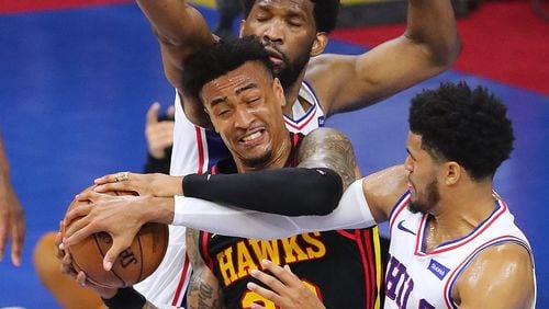 Hawks forward John Collins grabs the offensive rebound against Philadelphia 76ers center Joel Embiid and forward Tobias Harris, drawing a foul during Game 7 of the Eastern Conference semifinals Sunday, June 20, 2021, in Philadelphia. (Curtis Compton / Curtis.Compton@ajc.com)