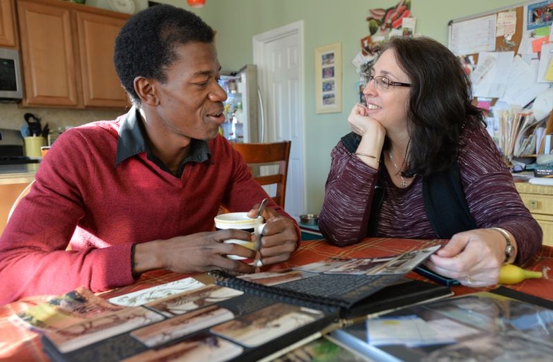 Samuel Johnson (left) talks as Teresa Cook shows her family photos from Kenya while they have a tea time together at Teresa's home, where Samuel and his wife Mary Thompson stay, on Saturday, November 22, 2014. HYOSUB SHIN / HSHIN@AJC.COM
