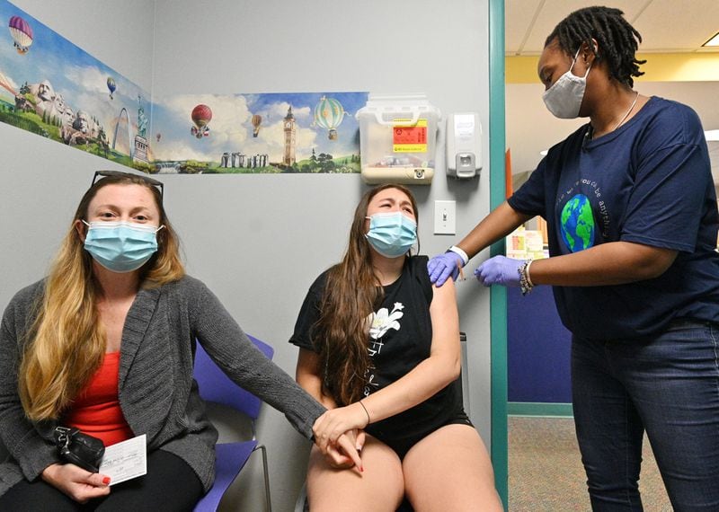May 12, 2021 Decatur - Lucy Saravia, 13, receives a first dose of the Pfizer-BioNTech vaccine from Pheona Mack (right), RMA, as her mother Robin Mead (left) comforts her at Dekalb Pediatric Center on Wednesday, May 12, 2021. More than a thousand patients, most of them 12-15 years old, had seized the opportunity to get a shot of the Pfizer-BioNTech vaccine at the clinic, which is partnering with the local school system to vaccinate students. (Hyosub Shin / Hyosub.Shin@ajc.com)