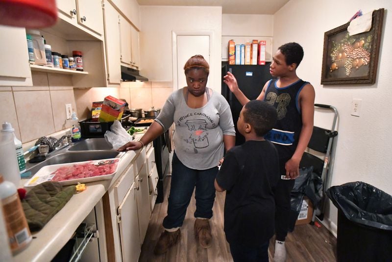 Alexis Cargile talks to sons Logan, 7, and Zach, 13, as she cooks dinner at their apartment in the complex formerly known as The Life at Greenbriar. She and her husband want to move but can’t afford the hundreds of dollars in application fees, security deposits and other expenses a new place would require. (Hyosub Shin / Hyosub.Shin@ajc.com)