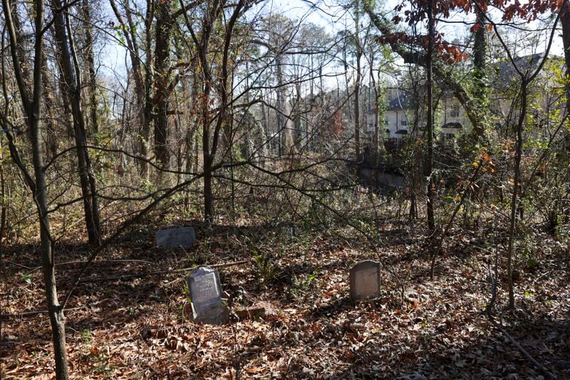 The Bluffs at Lenox townhome development in Buckhead can barely be seen through overgrown vegetation in the adjacent Piney Grove Cemetery. The development's homeowners association denies allegations that it is shirking its responsibility to maintain the cemetery. (Jason Getz / Jason.Getz@ajc.com)