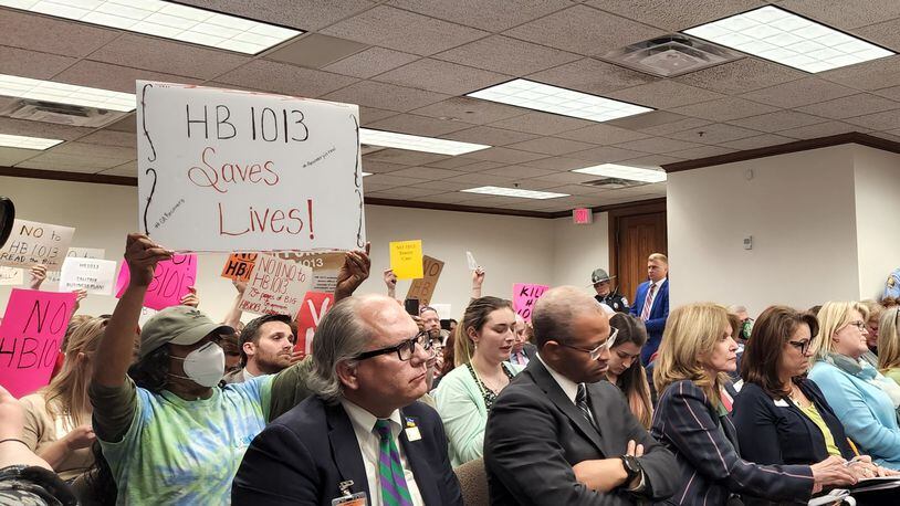 Supporters and opponents of a bill aiming to overhaul mental health care in Georgia hold signs during a Senate committee meeting. Maya T. Prabhu/maya.prabhu@ajc.com