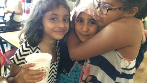 The author's daughter Celia, right, hugs her classmate, who is returning to Iraq for the summer, alongside a student who arrived new this year and adapted quickly.