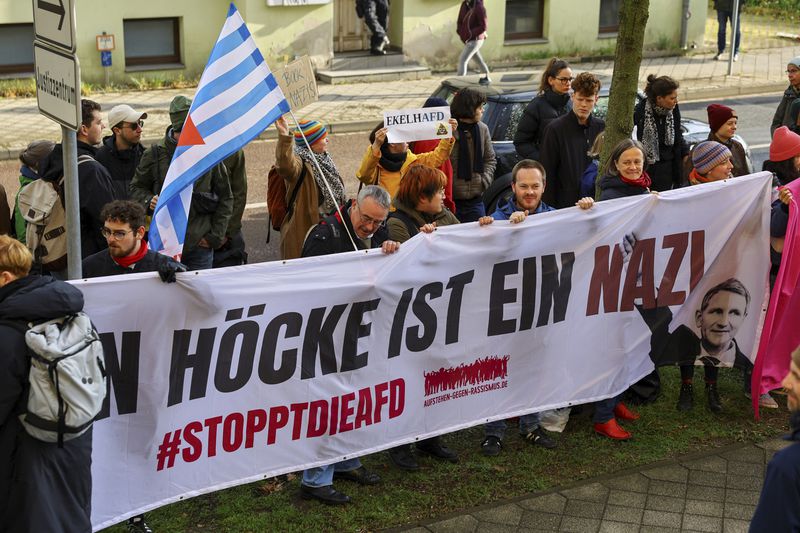Protestors hold a banner reading 'Bjoern Hoecke is a nazi' outside the state court in Halle, Germany, Thursday, April 18, 2024. Bjoern Hoecke, goes on trial at the state court in Halle on charges related to his alleged use in a 2021 speech of a slogan used by the Nazis' SA stormtroopers. (Fabrizio Bensch/Pool via AP)