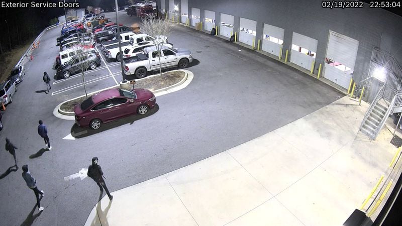 A still of security camera footage released by DeKalb police shows at least five suspects walking through the Courtesy Chrysler Dodge car dealership's parking lot. 