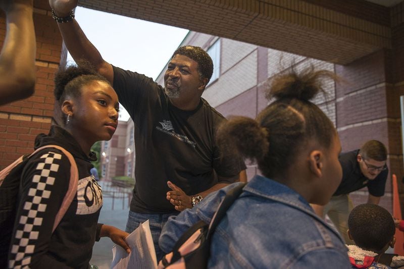 Lamont Jones (center), co-founder of the Furthering Fathering Corporation, gives M. Agnes Jones Elementary School students high-fives as they prepare to enter the school during the national Million Fathers March Day in Atlanta. ALYSSA POINTER / ALYSSA.POINTER@AJC.COM